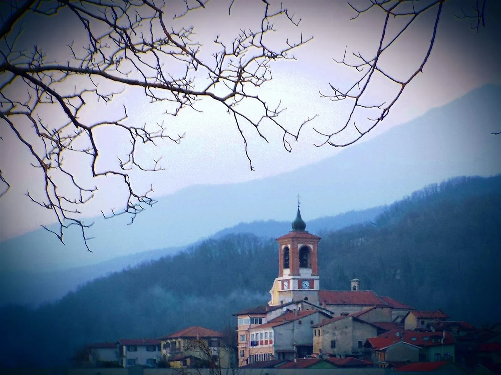 Il campanile di Palazzo Canavese con la lunga linea boscosa della Serra di Ivrea sullo sfondo