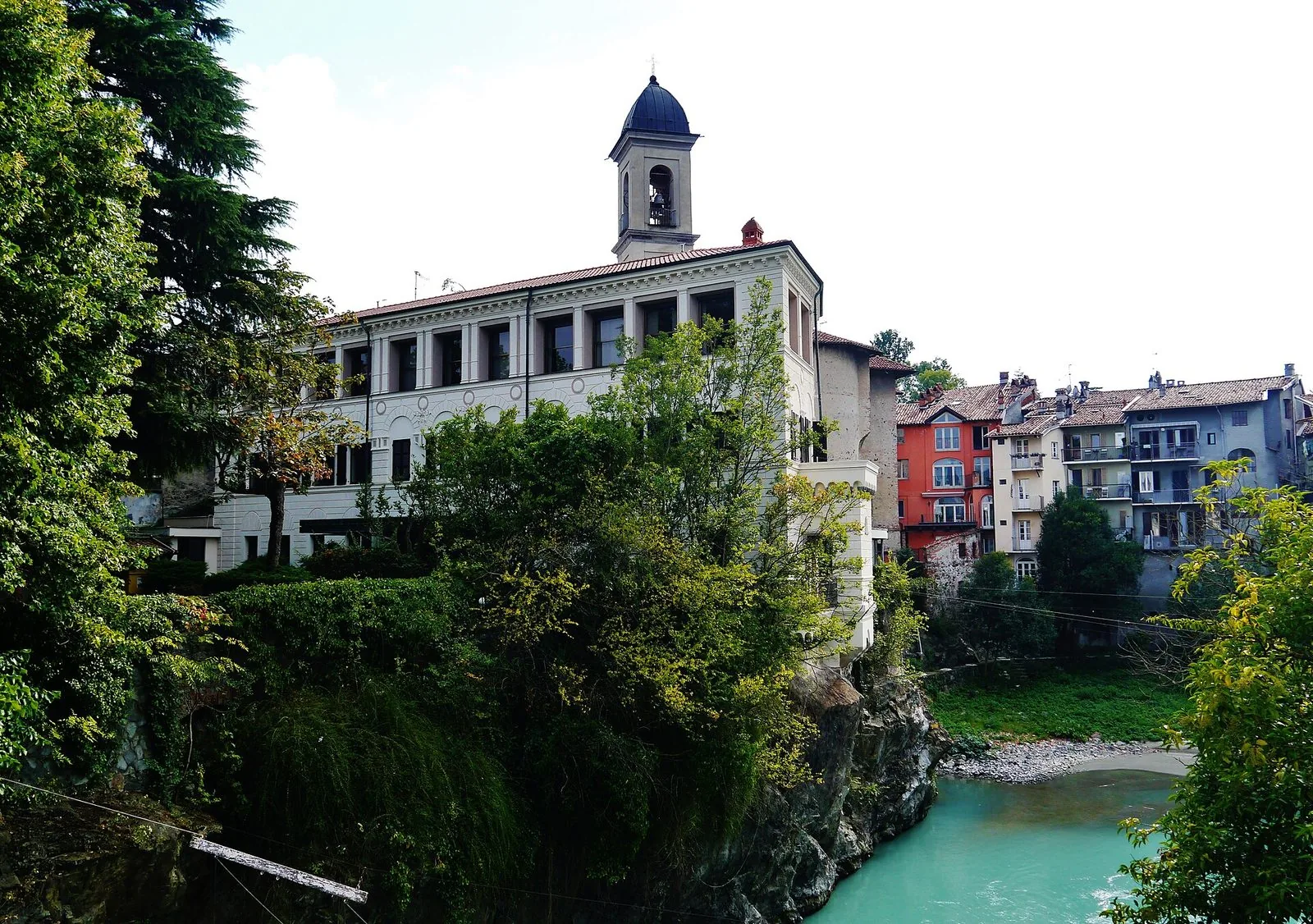 La Dora Baltea color smeraldo che scorre tra rocce e vegetazione nel centro di Ivrea, con edifici storici sulla riva