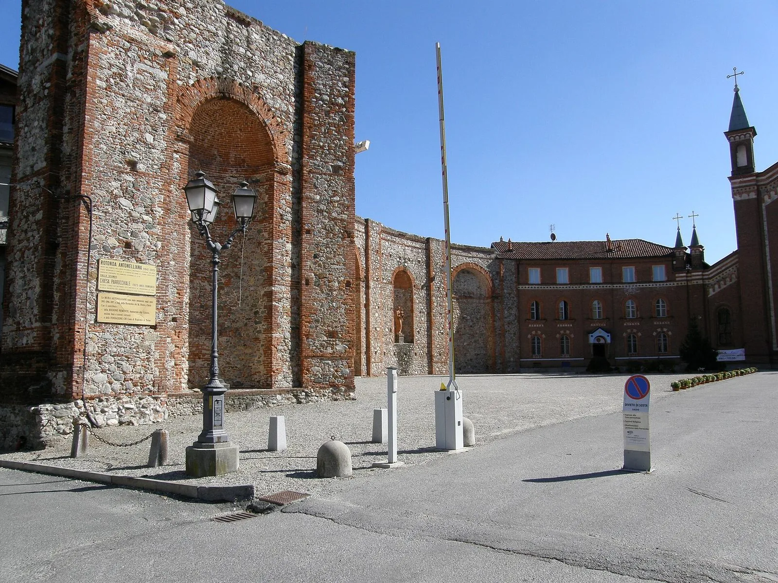 Le alte mura in mattoni della Rotonda Antonelliana a Castellamonte con la chiesa parrocchiale sullo sfondo
